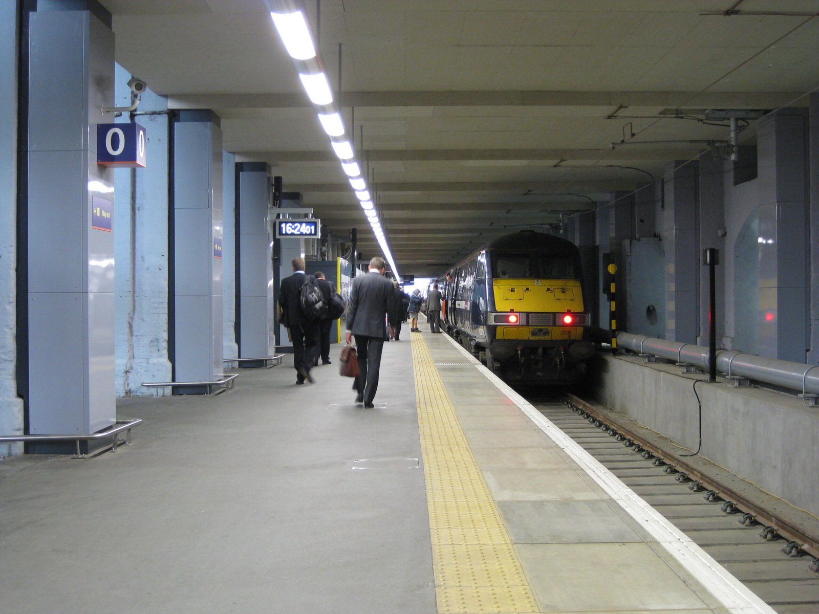 Passengers walk along a covered train platform beside a waiting train at King's Cross station in London.